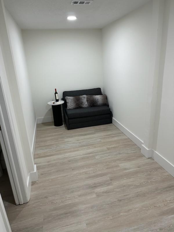 sitting room featuring light wood-type flooring, visible vents, and baseboards