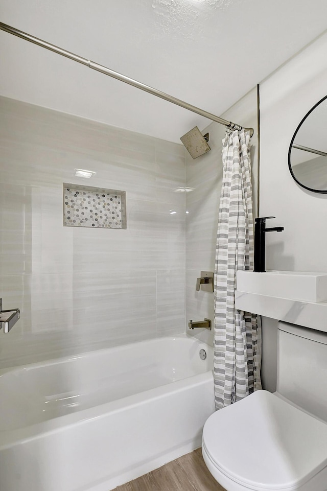 full bath featuring toilet, shower / bathtub combination with curtain, a sink, and wood finished floors