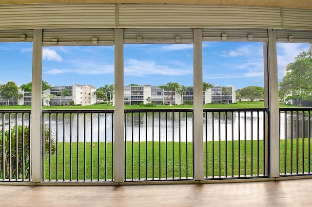 unfurnished sunroom with plenty of natural light, a water view, and a residential view