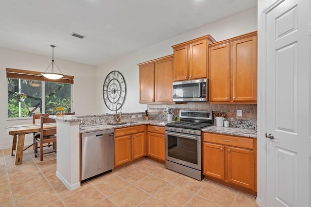 kitchen featuring visible vents, a peninsula, a sink, stainless steel appliances, and backsplash