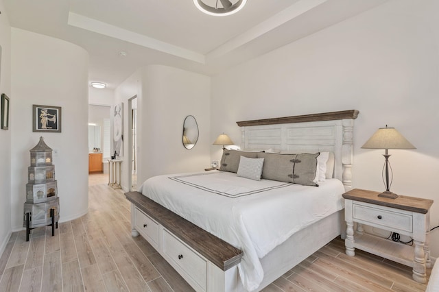 bedroom featuring a tray ceiling, wood finish floors, connected bathroom, and baseboards