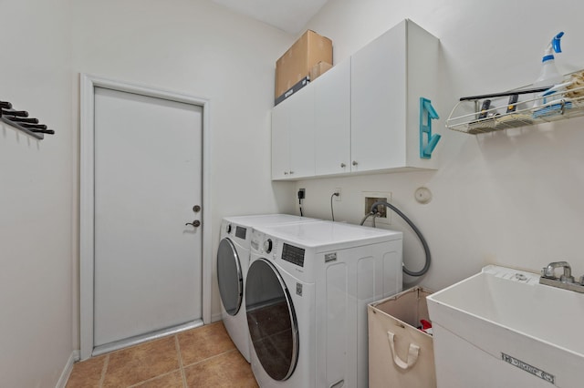 laundry area with washing machine and clothes dryer, light tile patterned floors, cabinet space, a sink, and baseboards