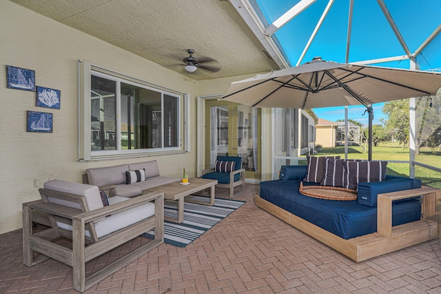 view of patio with glass enclosure, ceiling fan, and an outdoor living space