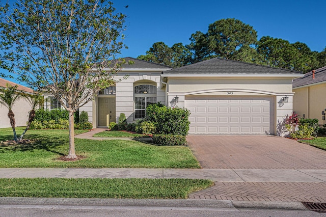 ranch-style home featuring decorative driveway, an attached garage, a front lawn, and stucco siding