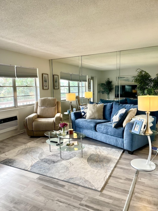 living area featuring a textured ceiling, an AC wall unit, and wood finished floors