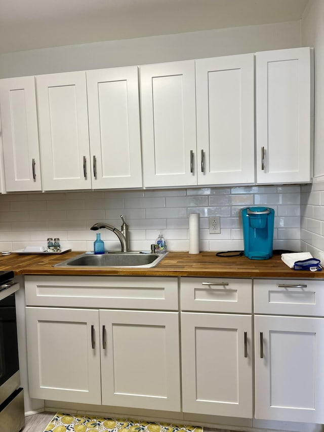 interior space featuring white cabinets, wood counters, backsplash, and a sink