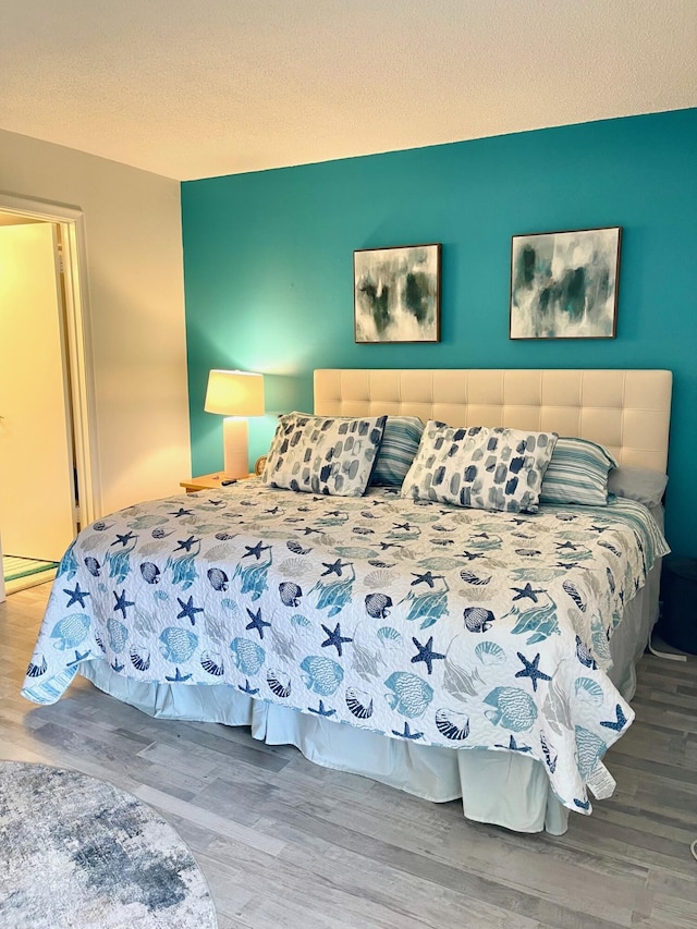 bedroom featuring a textured ceiling, baseboard heating, and wood finished floors