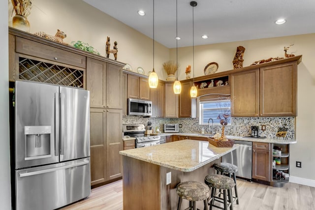 kitchen with tasteful backsplash, appliances with stainless steel finishes, light stone counters, a center island, and a kitchen bar