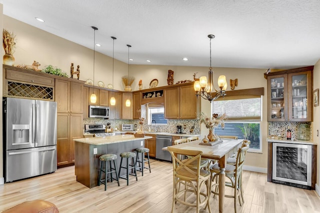 kitchen featuring beverage cooler, light wood-style flooring, appliances with stainless steel finishes, vaulted ceiling, and a sink