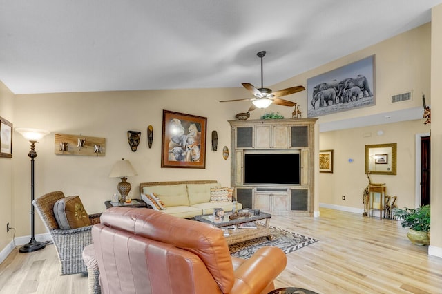 living room featuring lofted ceiling, light wood-style flooring, a ceiling fan, visible vents, and baseboards