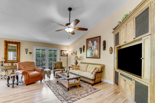 living area featuring baseboards, light wood-style flooring, ceiling fan, vaulted ceiling, and a textured ceiling