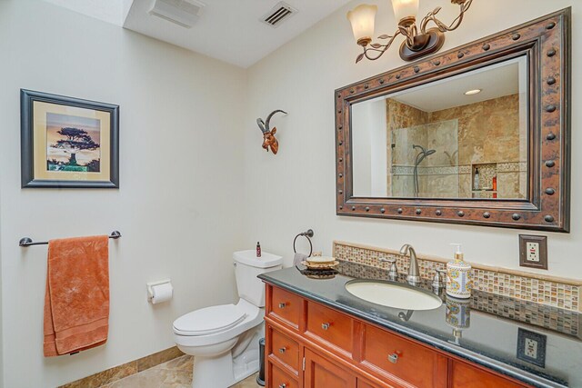 bathroom with toilet, vanity, visible vents, a tile shower, and an inviting chandelier