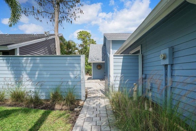 view of side of property featuring fence and roof with shingles