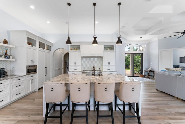 kitchen with open shelves, light wood-type flooring, arched walkways, and open floor plan