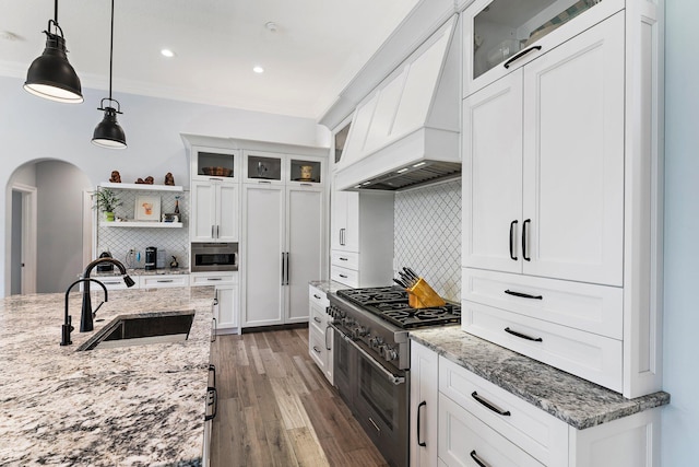 kitchen featuring high end stainless steel range, a sink, open shelves, arched walkways, and custom exhaust hood