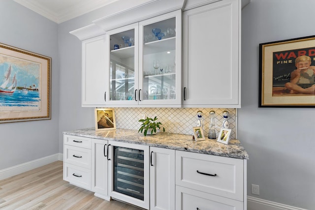 bar featuring decorative backsplash, baseboards, beverage cooler, and ornamental molding