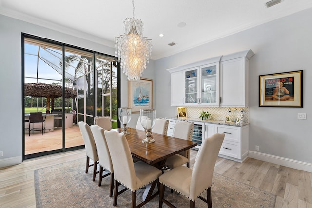 dining area with an inviting chandelier, light wood-style floors, baseboards, and ornamental molding