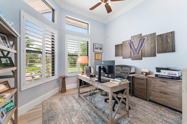 office featuring wood finished floors, a towering ceiling, crown molding, baseboards, and ceiling fan