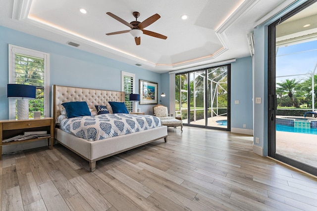 bedroom with a tray ceiling, visible vents, access to exterior, and light wood finished floors