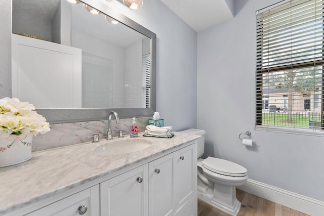 bathroom with vanity, toilet, wood finished floors, and baseboards