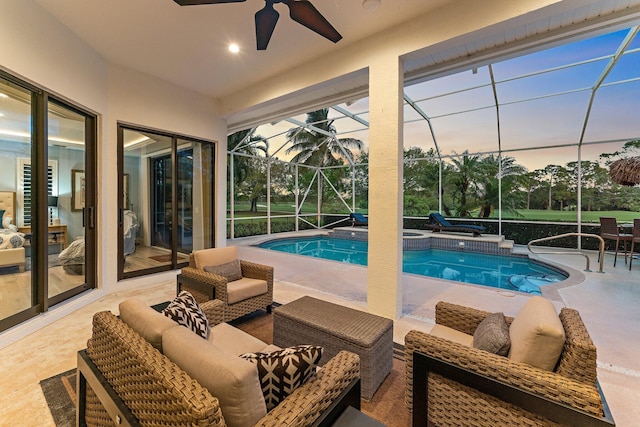 pool at dusk featuring glass enclosure, a patio, outdoor lounge area, and ceiling fan