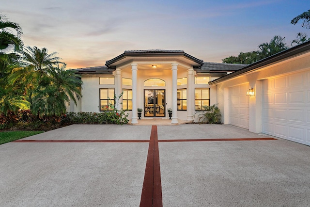 view of front of property with french doors, driveway, and stucco siding