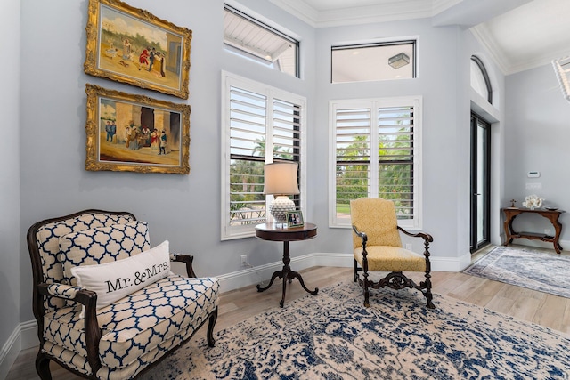 living area with crown molding, wood finished floors, and baseboards