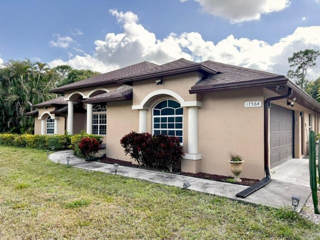 mediterranean / spanish home with a garage, roof with shingles, a front lawn, and stucco siding