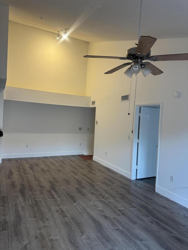 interior space with high vaulted ceiling, a ceiling fan, visible vents, baseboards, and dark wood-style floors