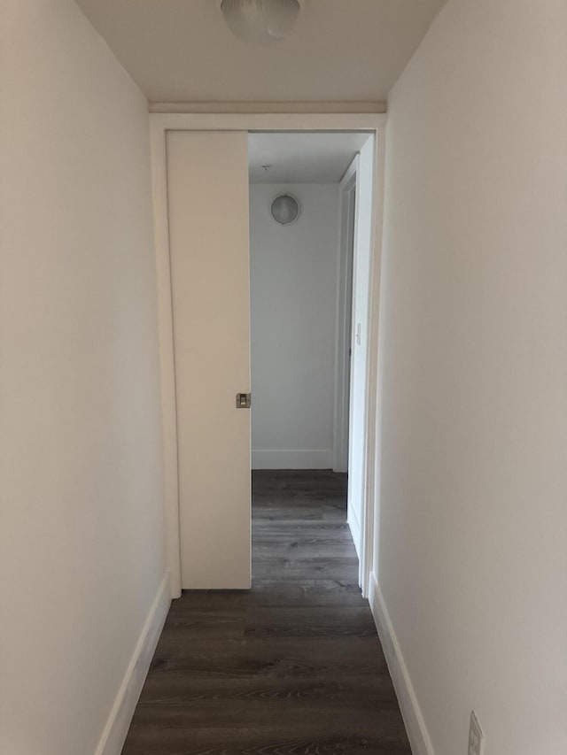 hallway with dark wood-style floors and baseboards