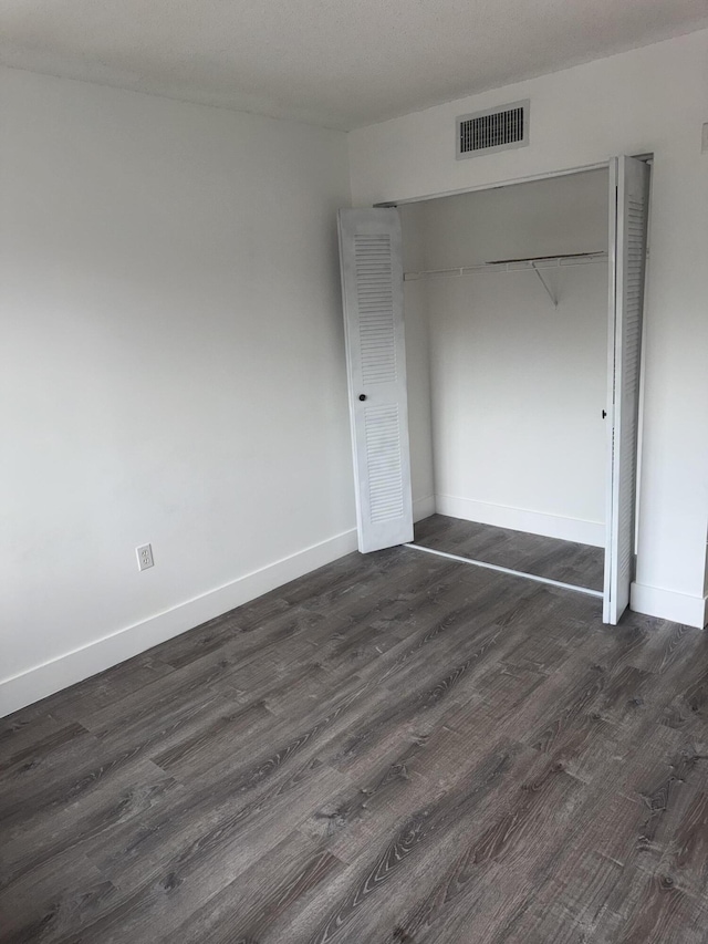 unfurnished bedroom featuring baseboards, visible vents, and dark wood finished floors