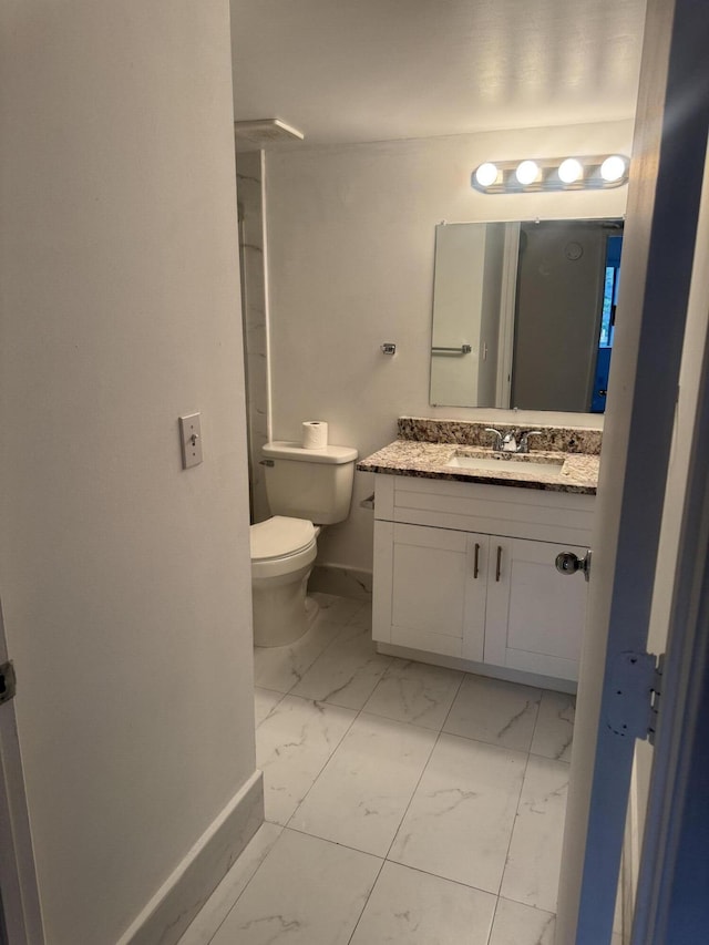 bathroom with toilet, marble finish floor, baseboards, and vanity