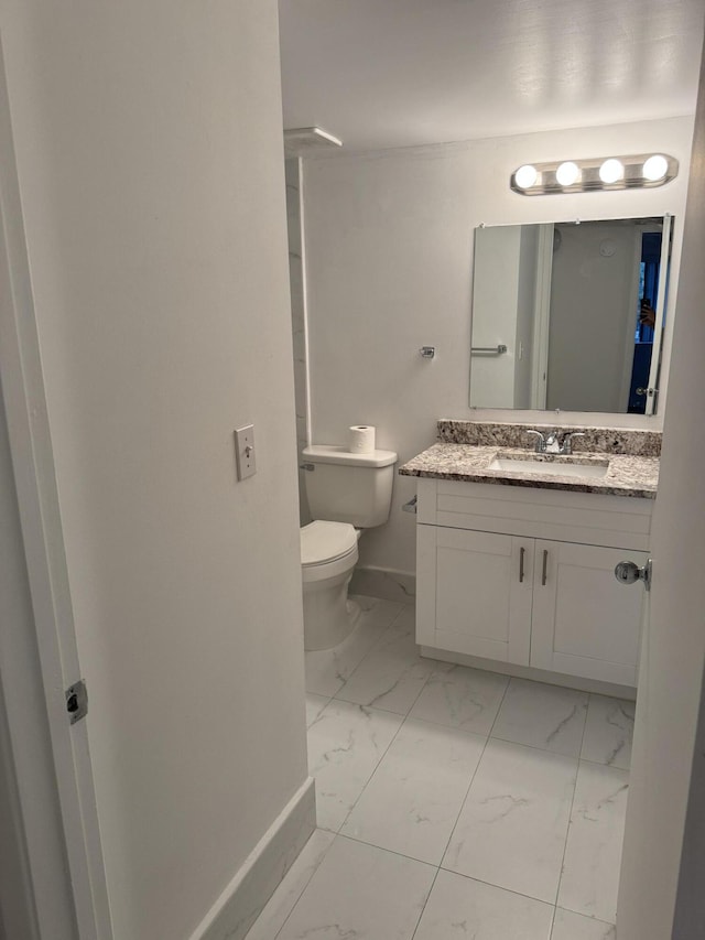 bathroom featuring toilet, marble finish floor, baseboards, and vanity