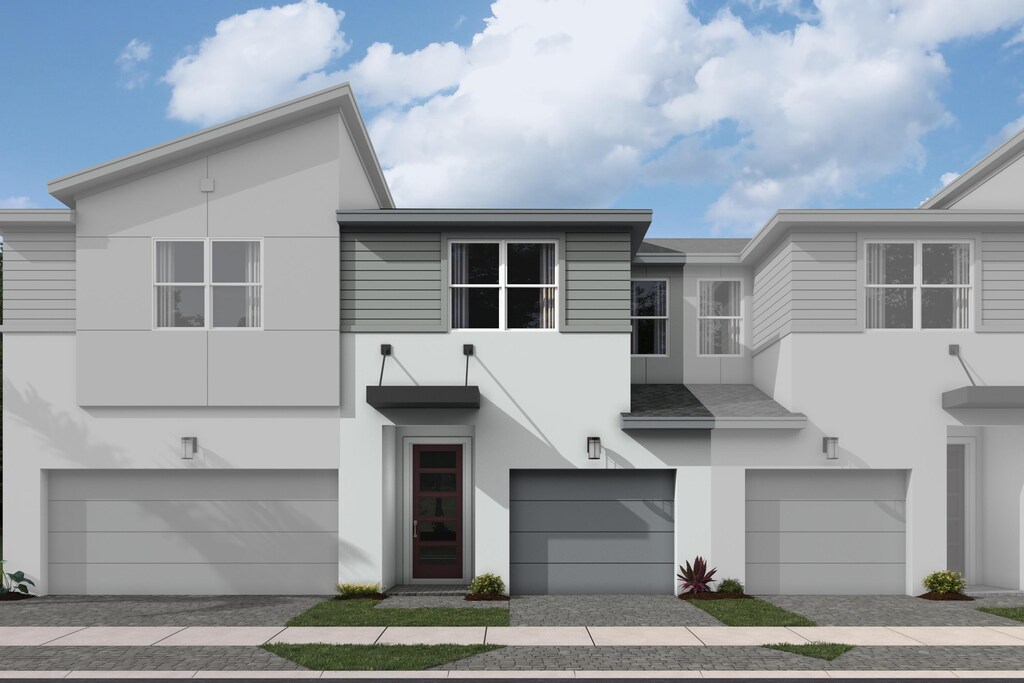 townhome / multi-family property featuring decorative driveway, an attached garage, and stucco siding