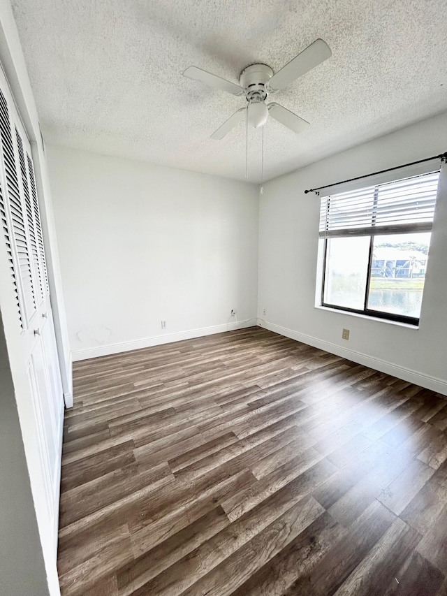 unfurnished bedroom featuring a closet, baseboards, and dark wood-style flooring