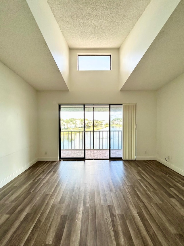 empty room featuring dark wood-style floors, plenty of natural light, and baseboards