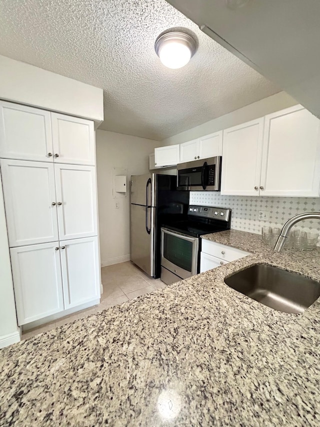 kitchen with stainless steel appliances, a sink, white cabinetry, and decorative backsplash