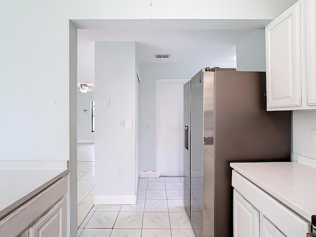 kitchen featuring light stone countertops, baseboards, visible vents, light tile patterned flooring, and white cabinets