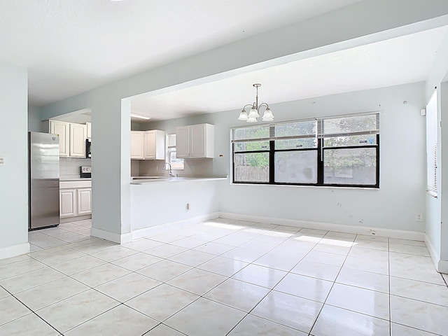 interior space with a chandelier, light tile patterned floors, plenty of natural light, and baseboards