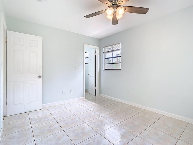 spare room with light tile patterned floors, a ceiling fan, and baseboards