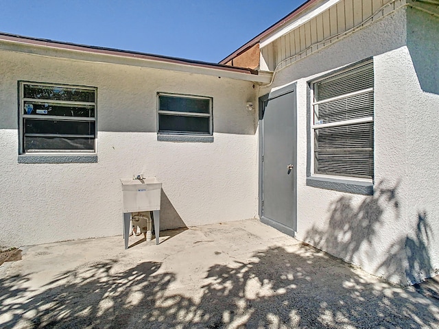 property entrance with stucco siding and a patio