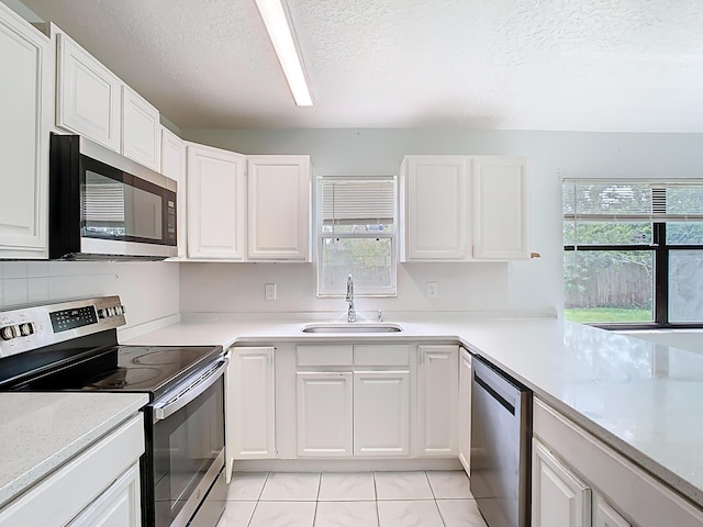 kitchen featuring light countertops, stainless steel appliances, a textured ceiling, white cabinetry, and a sink