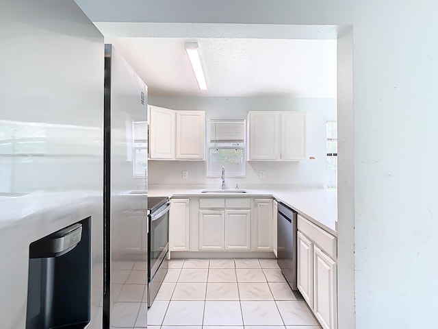 kitchen featuring appliances with stainless steel finishes, white cabinetry, light countertops, and a sink