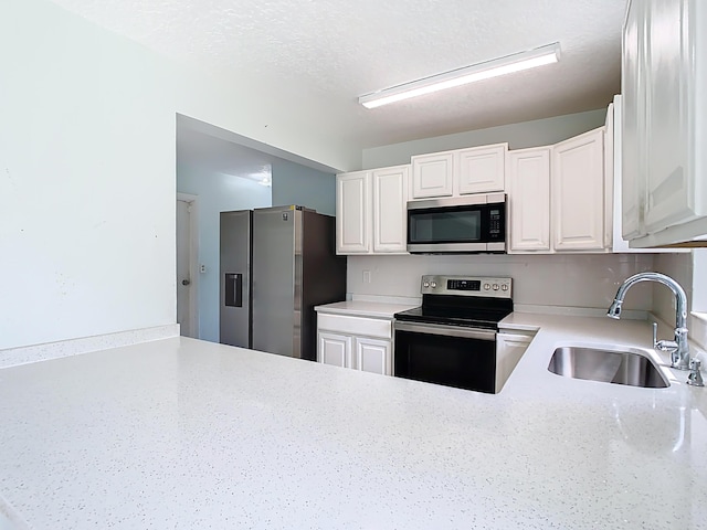 kitchen with a sink, a textured ceiling, appliances with stainless steel finishes, and white cabinets