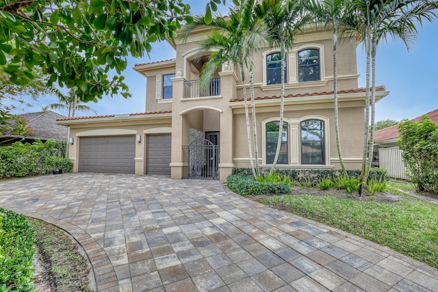 mediterranean / spanish-style house with decorative driveway, a tile roof, a balcony, and stucco siding