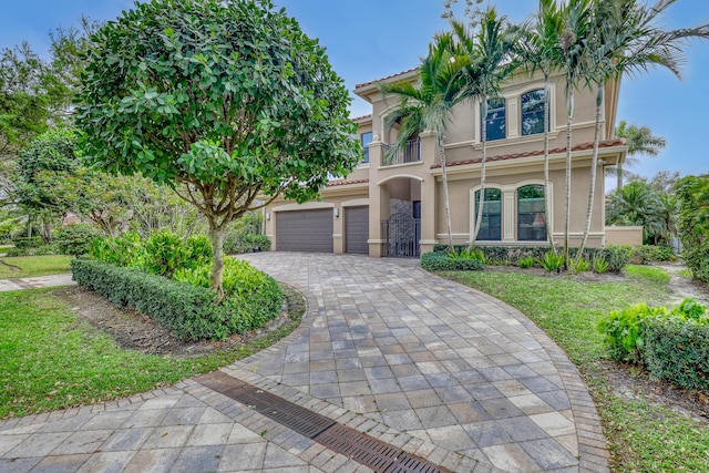 view of front facade featuring decorative driveway, a tile roof, an attached garage, and stucco siding