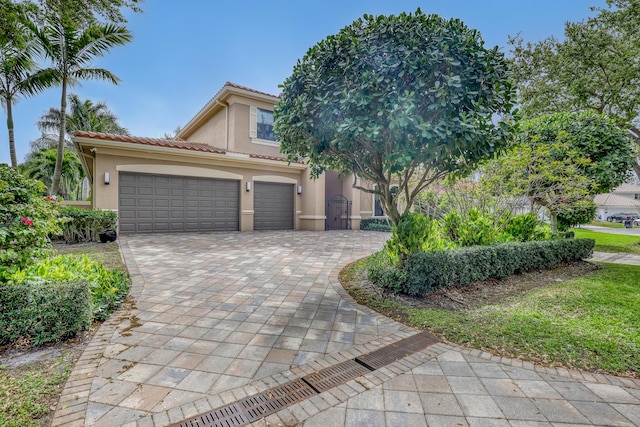 view of front facade featuring a tiled roof, decorative driveway, and stucco siding