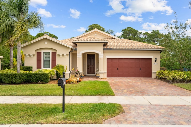 mediterranean / spanish home with decorative driveway, a tile roof, stucco siding, an attached garage, and a front lawn