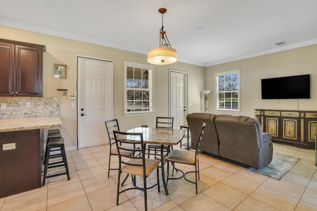 dining space with light tile patterned flooring, visible vents, baseboards, and ornamental molding