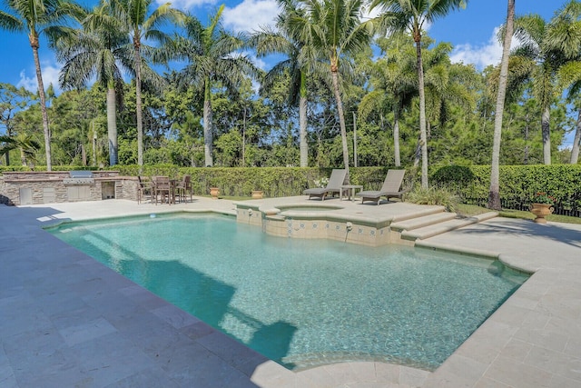 view of swimming pool featuring a patio area, a pool with connected hot tub, and exterior kitchen